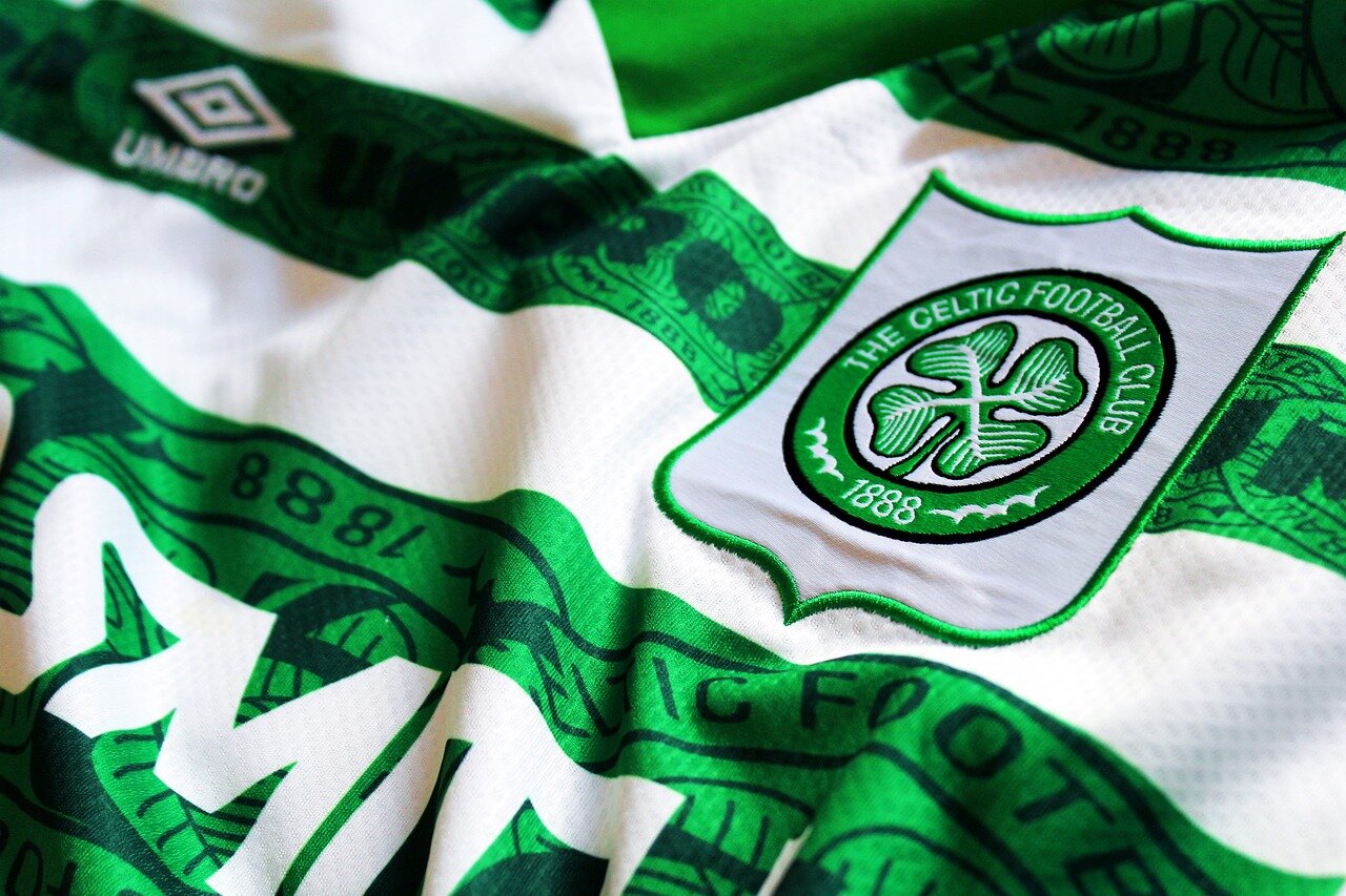Fans eagerly discussing the upcoming Scottish Cup match between Celtic and Auchinleck Talbot, showcasing their team colors and enthusiasm
