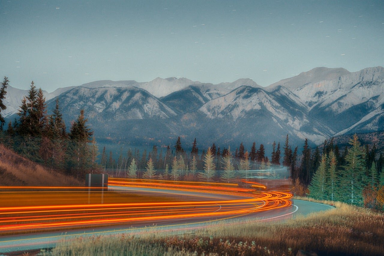 A serene countryside landscape, featuring winding roads surrounded by lush greenery and distant mountains, inviting players to explore