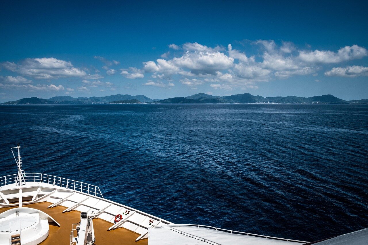 A group of individuals participates in a yoga class on the deck of a cruise ship, surrounded by serene ocean views and a clear blue sky.