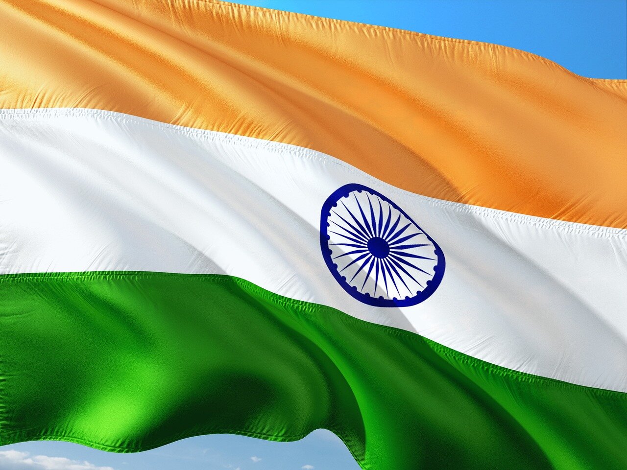 A group of Indian students stands outside a university building, discussing their concerns about rising tuition fees and stricter visa regulations as they consider their options for studying abroad.