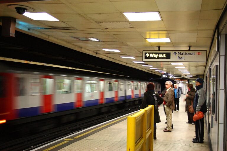 Commuters wait at a crowded London Underground station, glancing at departure boards as they prepare for the upcoming Tube strikes.