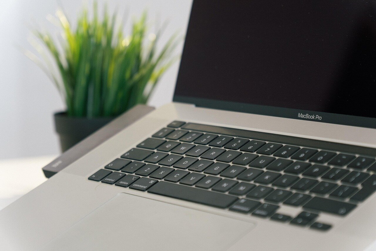 A tech reviewer tests the new MacBook Pro M5, showcasing its sleek design and vibrant display while running performance benchmarks in a modern workspace.