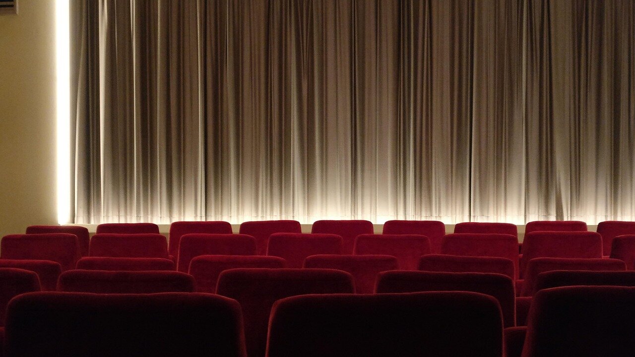 A group of viewers enthusiastically watches an action movie on a large screen in a cozy living room, surrounded by snacks and drinks.
