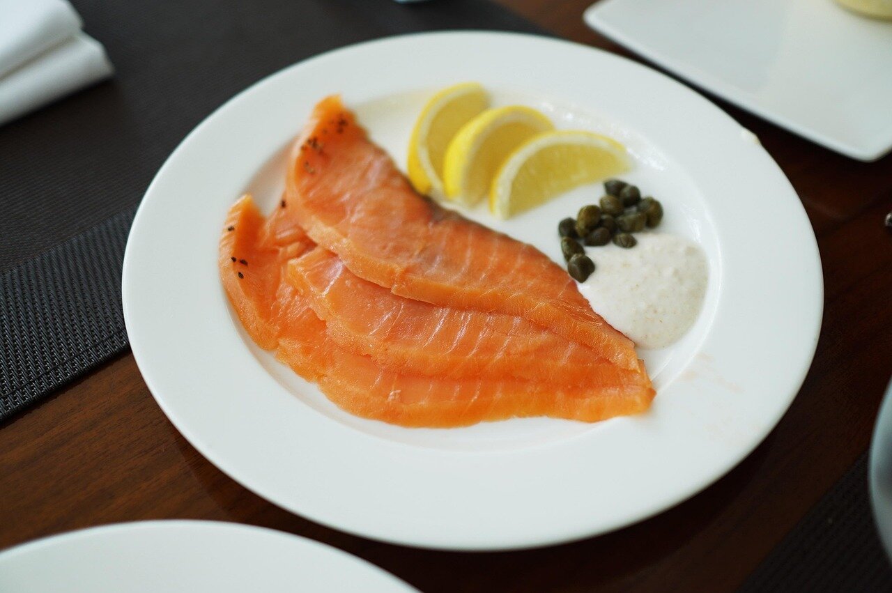 A closeup of wildcaught salmon fillets being seasoned with minimal spices, emphasizing the simplicity of the preparation process