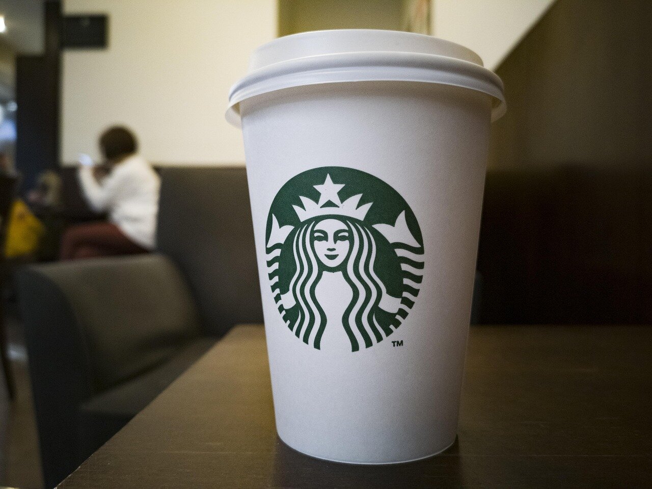 A barista at Starbucks looks concerned while interacting with a new AIpowered ordering system as customers wait in line.