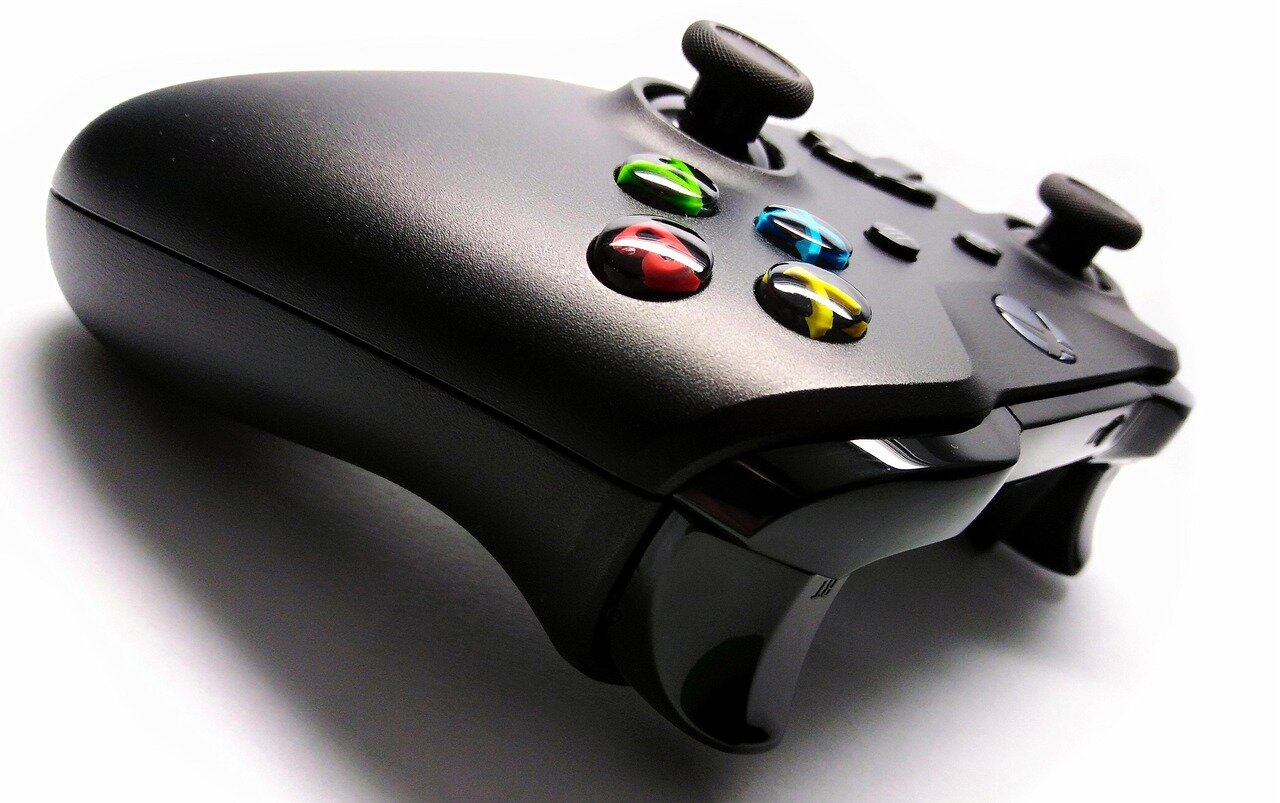 A crowd of enthusiastic gamers gathers in a large auditorium, eagerly watching the live stream of the Xbox Games Showcase 2026 on a massive screen, as colorful lights illuminate the stage.
