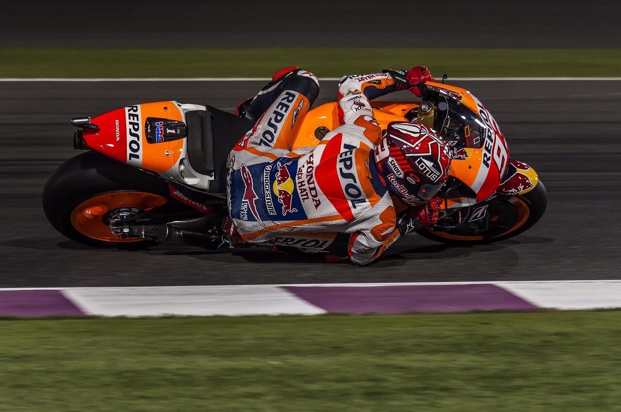 Ai Ogura celebrates his first MotoGP victory as he crosses the finish line, while the aftermath of Marco Bezzecchi's crash is visible in the background.