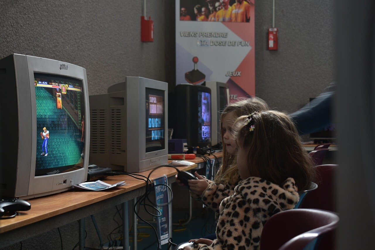 A group of gamers excitedly discusses the latest Nintendo downloads on their devices, surrounded by colorful merchandise and promotional displays in a gaming store.