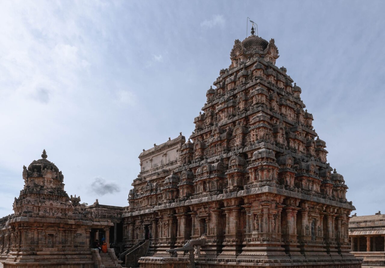 A bustling street near a historic temple filled with tourists and local vendors, highlighting the intersection of culture and commerce in Tamil Nadu